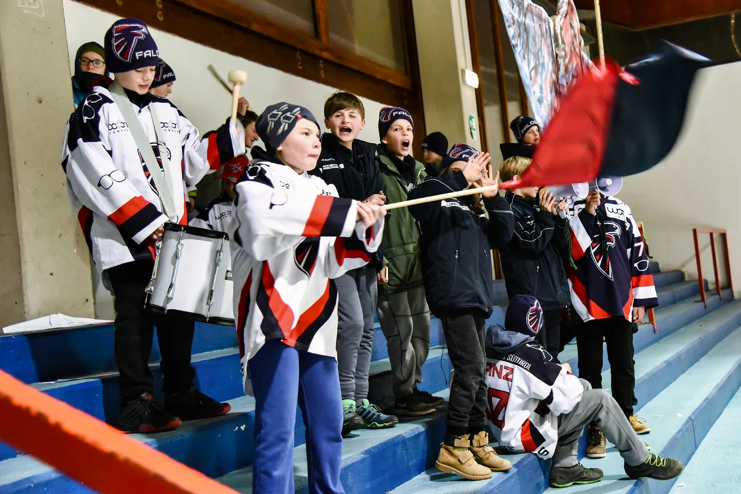 Giovani tifosi e giocatori fanno il tifo insieme con una bandiera del club.